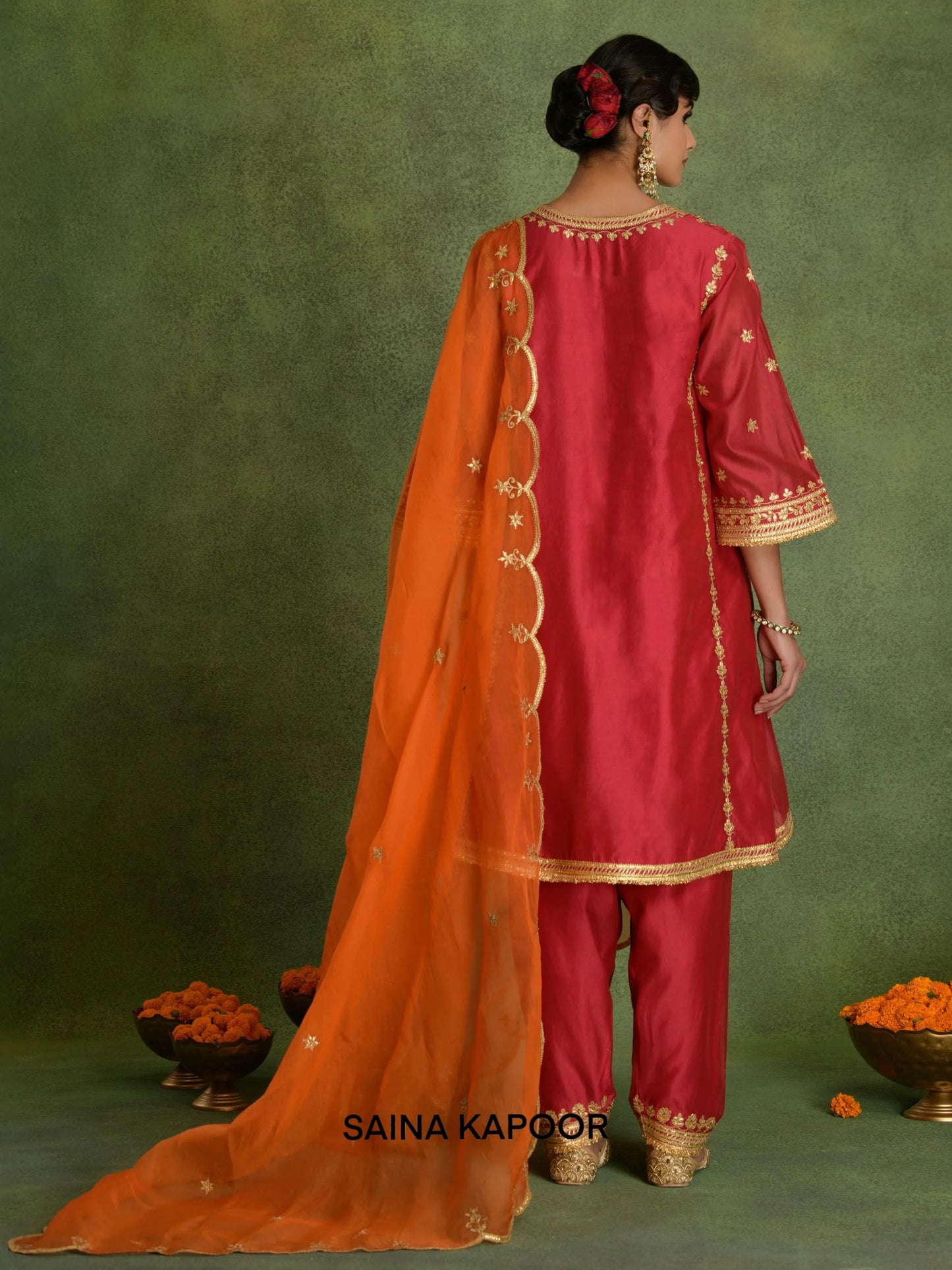 Back view of fuchsia Chanderi short kurta set for women showing three-quarter gota embroidered sleeve cuffs, gold gota side border & matching dhoti salwar with embroidered ankle cuffs — Saina Kapoor
