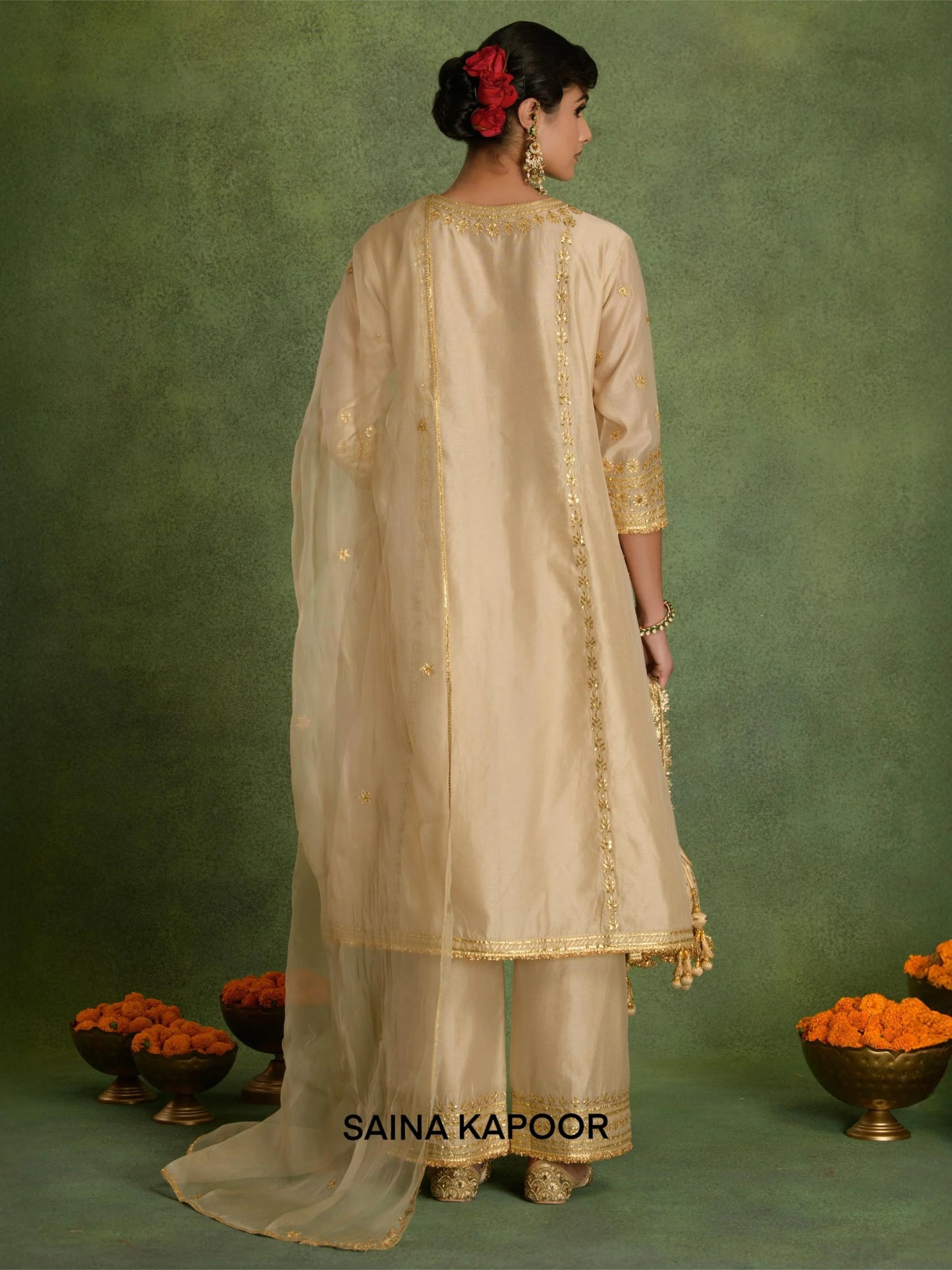 Back view of beige Chanderi long A-line kurta set for women showing three-quarter gota embroidered sleeve cuffs & matching wide-leg palazzo pants with gold gota tassel hem — Saina Kapoor