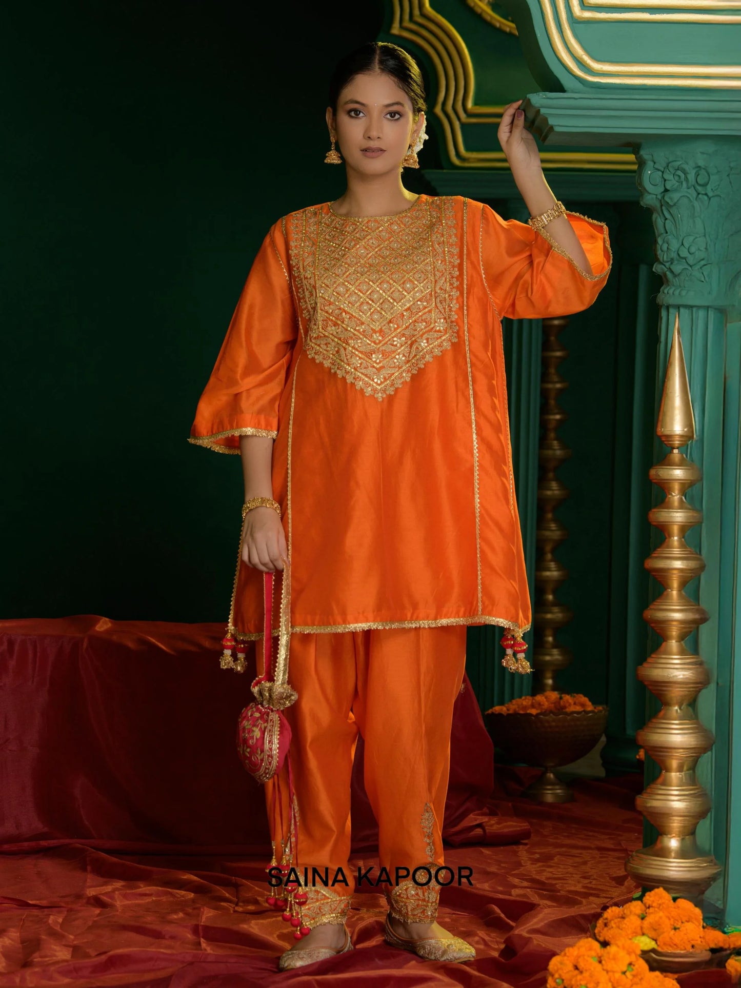 Deep orange Chanderi short choga with gold gota patti sequin embroidered yoke & matching dhoti salwar & pink potli bag — Saina Kapoor
