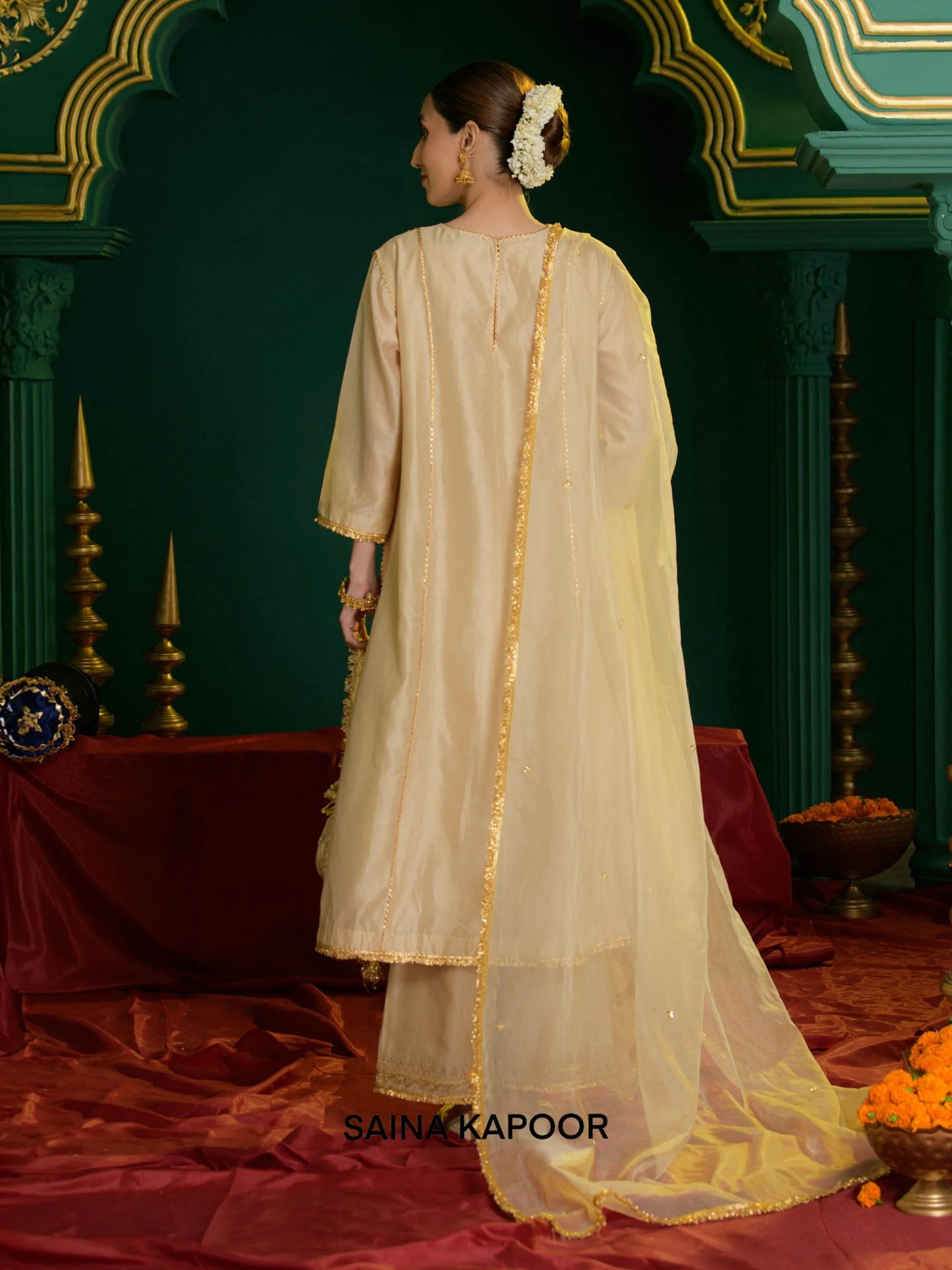 Back view of beige Chanderi A-line kurta set for women showing three-quarter sleeves with gota embroidered cuffs & matching wide-leg palazzo pants — Saina Kapoor