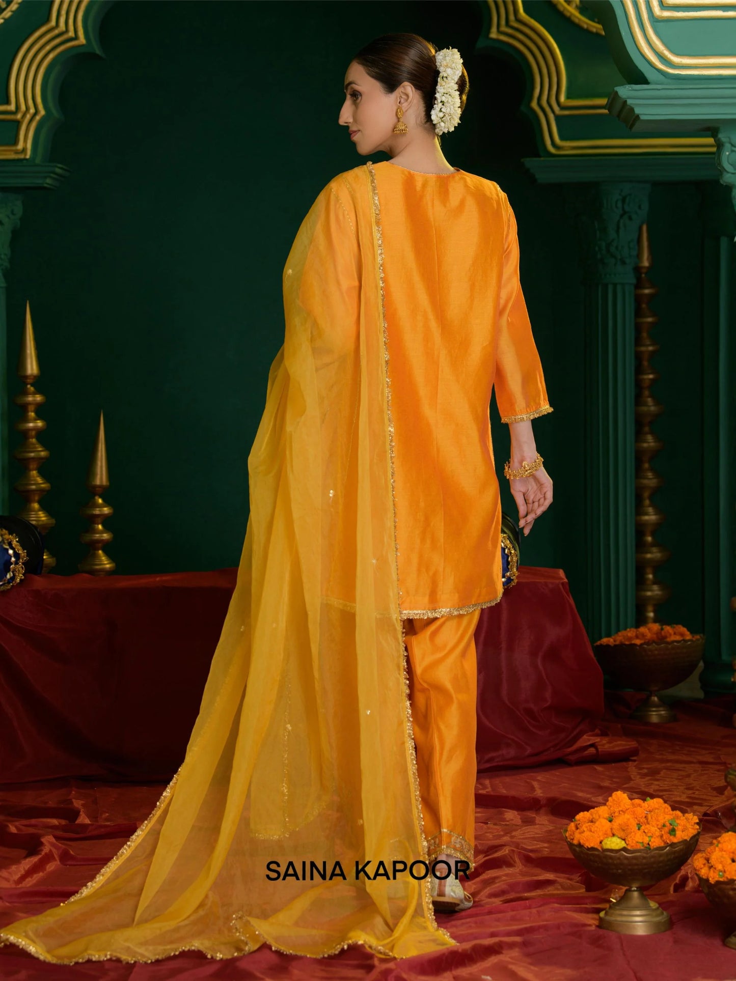 Back view of orange marigold Chanderi short kurta set for women with draped organza dupatta & gota patti embroidered ankle cuff salwar — Saina Kapoor