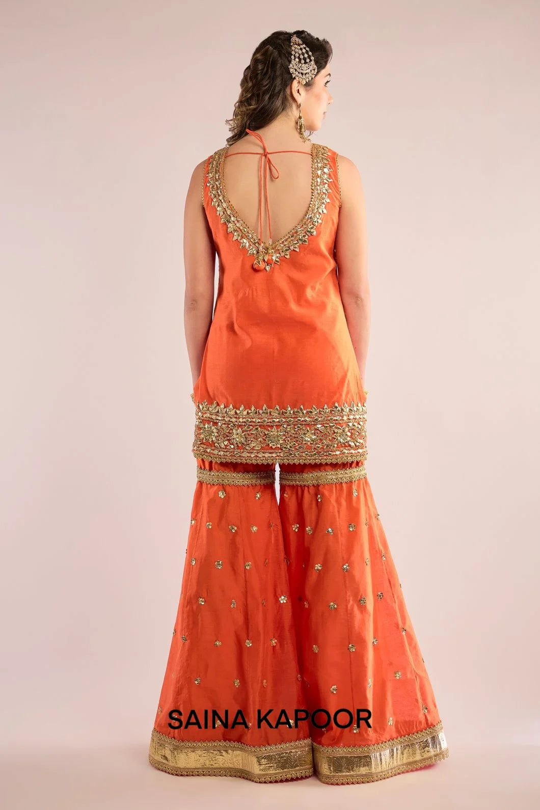 Back view of orange Chanderi kurti gharara set for women with draped orange organza dupatta — Saina Kapoor