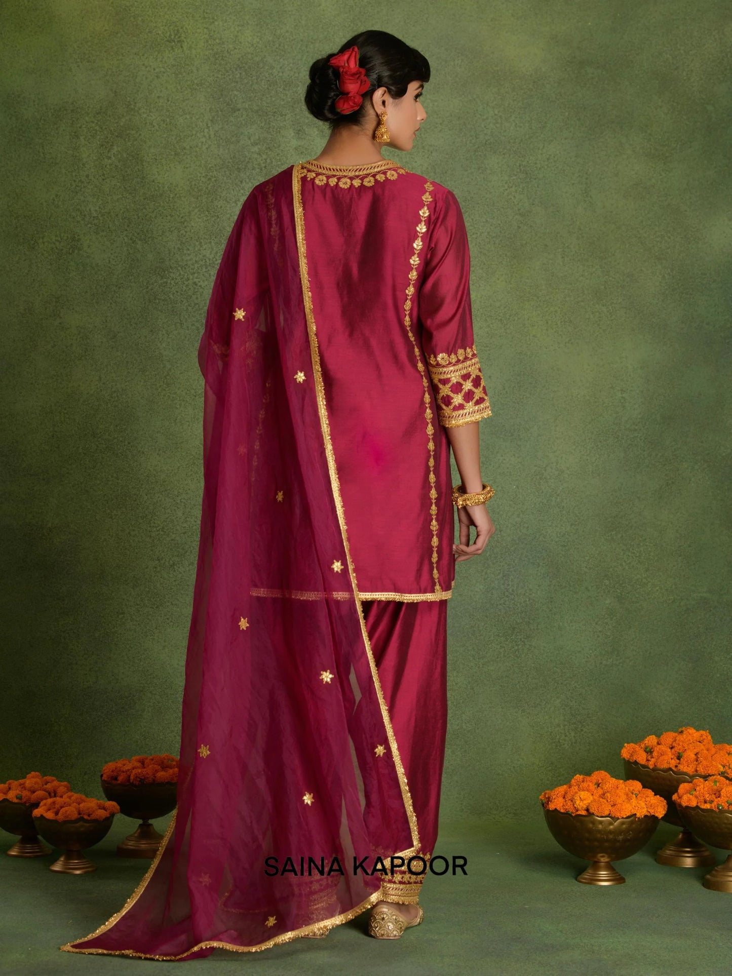 Back view of mulberry Chanderi short A-line kurta set for women showing three-quarter gota embroidered sleeve cuffs & matching dhoti salwar with gold gota ankle cuffs — Saina Kapoor