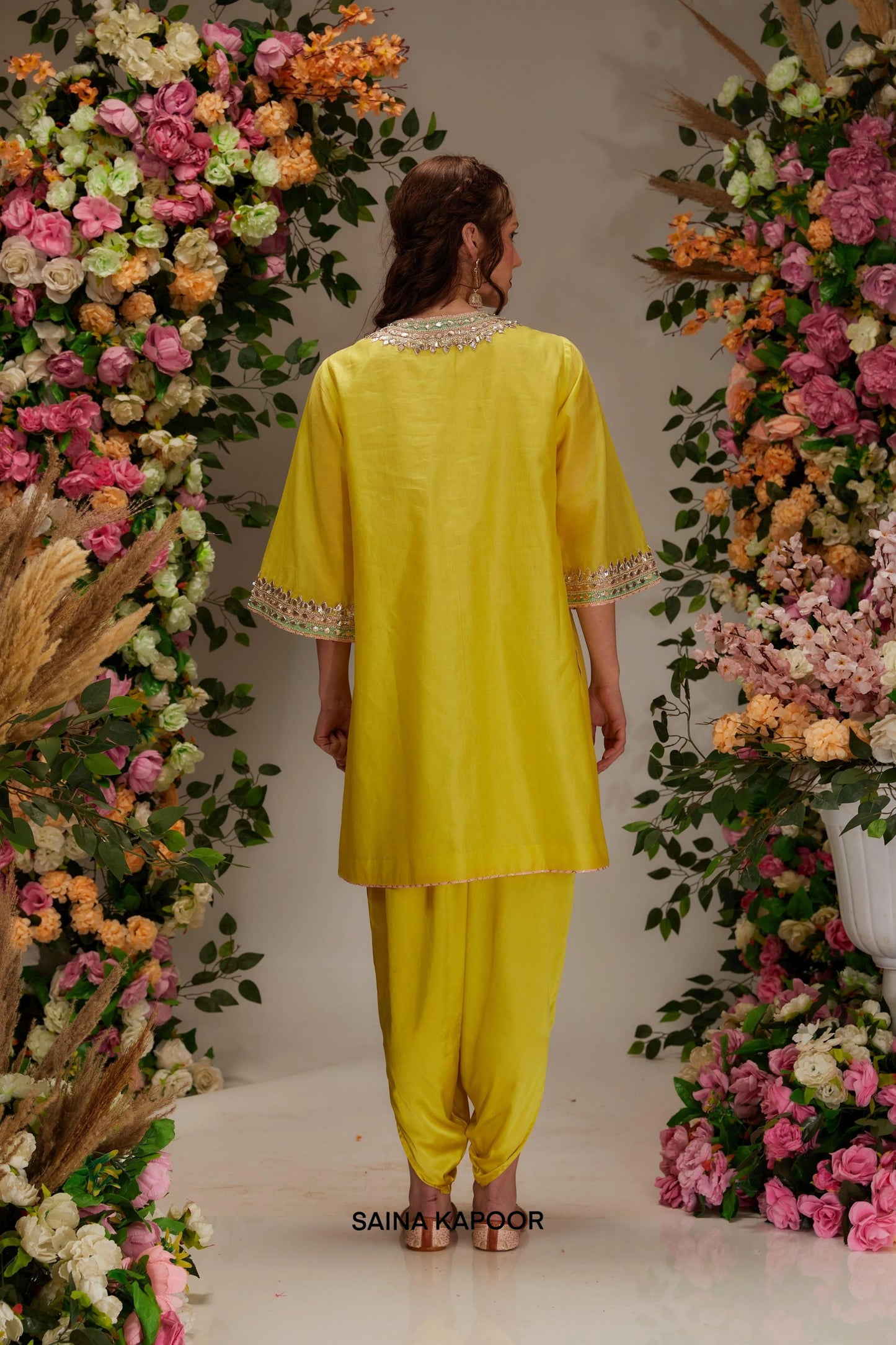 Back view of lime yellow Chanderi short kurta set for women showing gota sequin embroidered back neckline border, flared sleeve cuffs & matching dhoti pants — Saina Kapoor