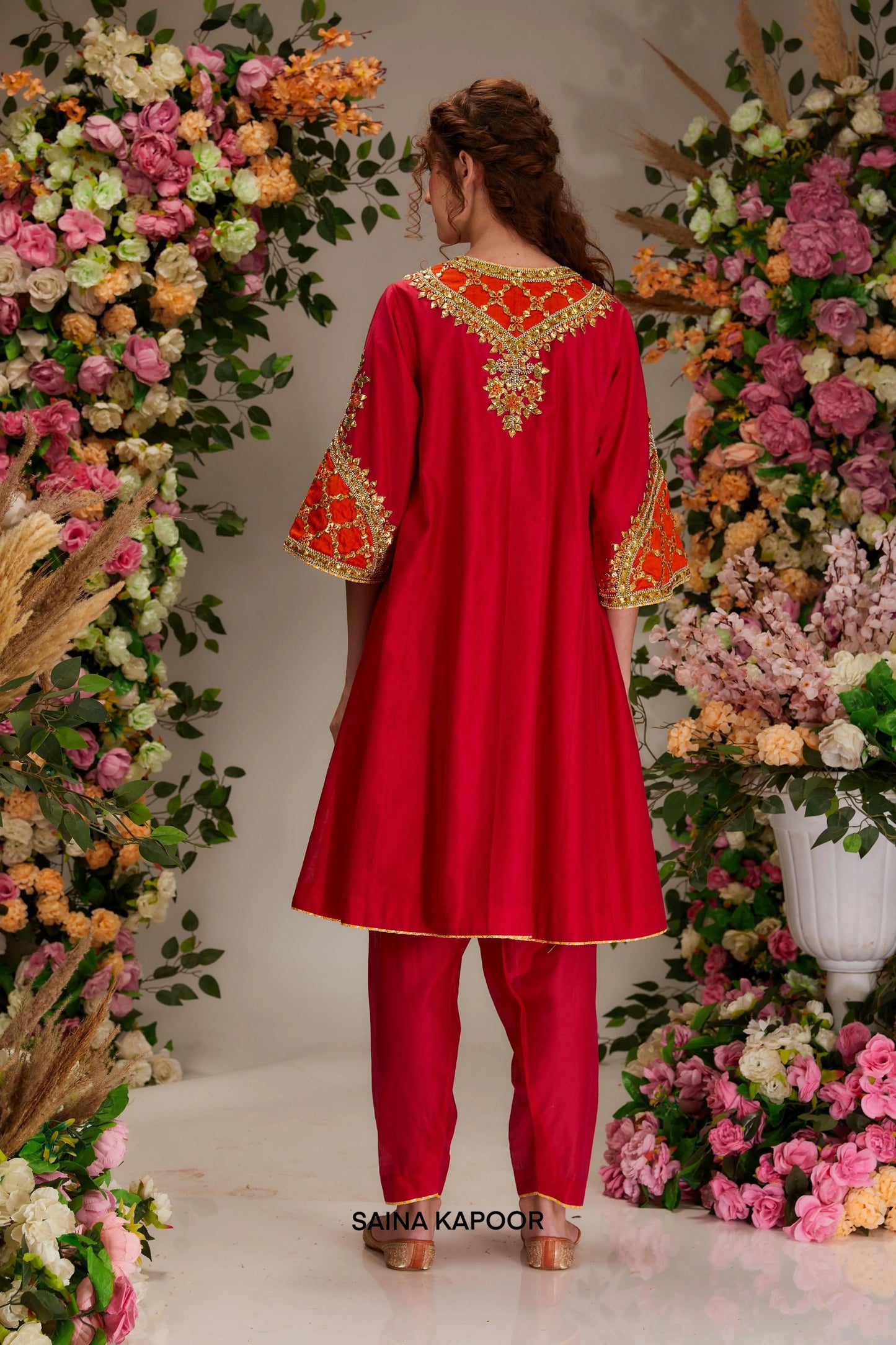Back view of red Chanderi long kalidar kurta set with elongated silhouette & orange organza dupatta — Saina Kapoor